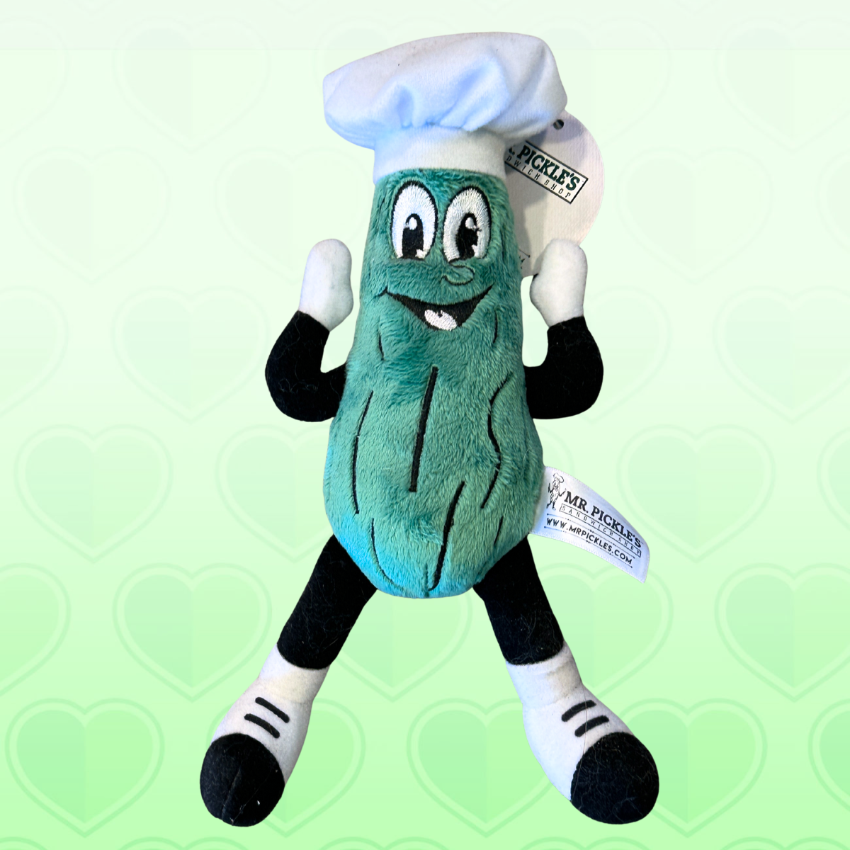 Plush toy resembling a pickle with a chef hat on a green background