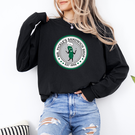 Person wearing a black sweatshirt with a green logo and text, standing against a white background.