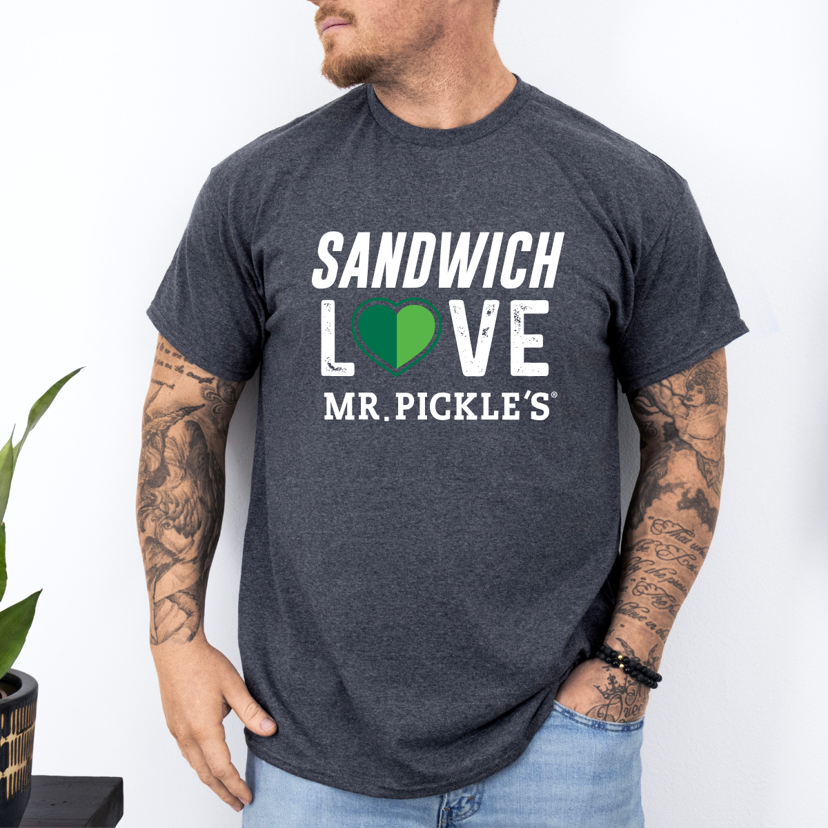 Person wearing a dark gray t-shirt with 'Sandwich Love Mr. Pickle's' text and green heart graphic.
