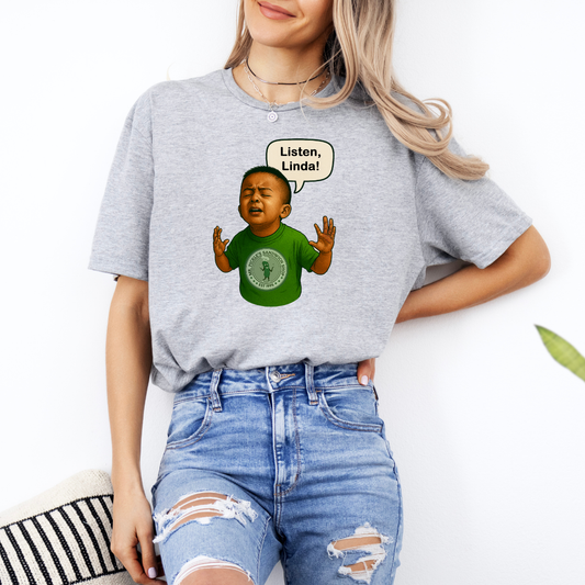 Person wearing a gray t-shirt with a graphic of a child and text, standing against a white background.