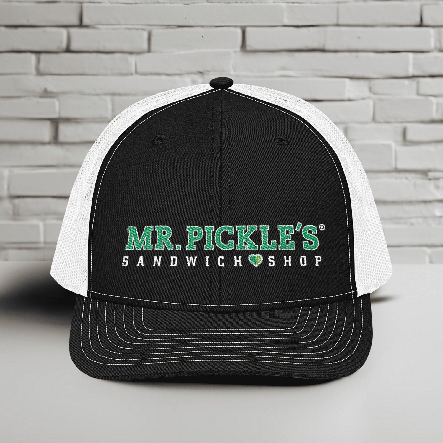 Black and white cap with 'Mr. Pickle's Sandwich Shop' text on a gray brick background