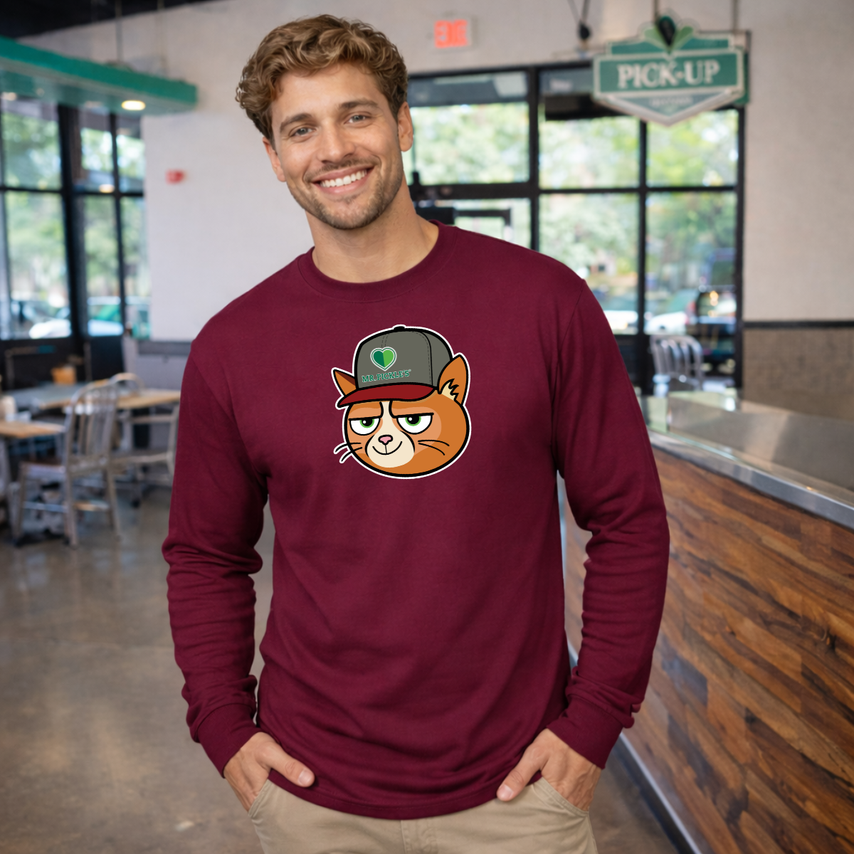 Man wearing a maroon long-sleeve shirt with a cat graphic in a casual setting