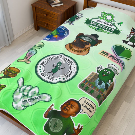 Green bedspread with various graphics and text on a bed in a room.
