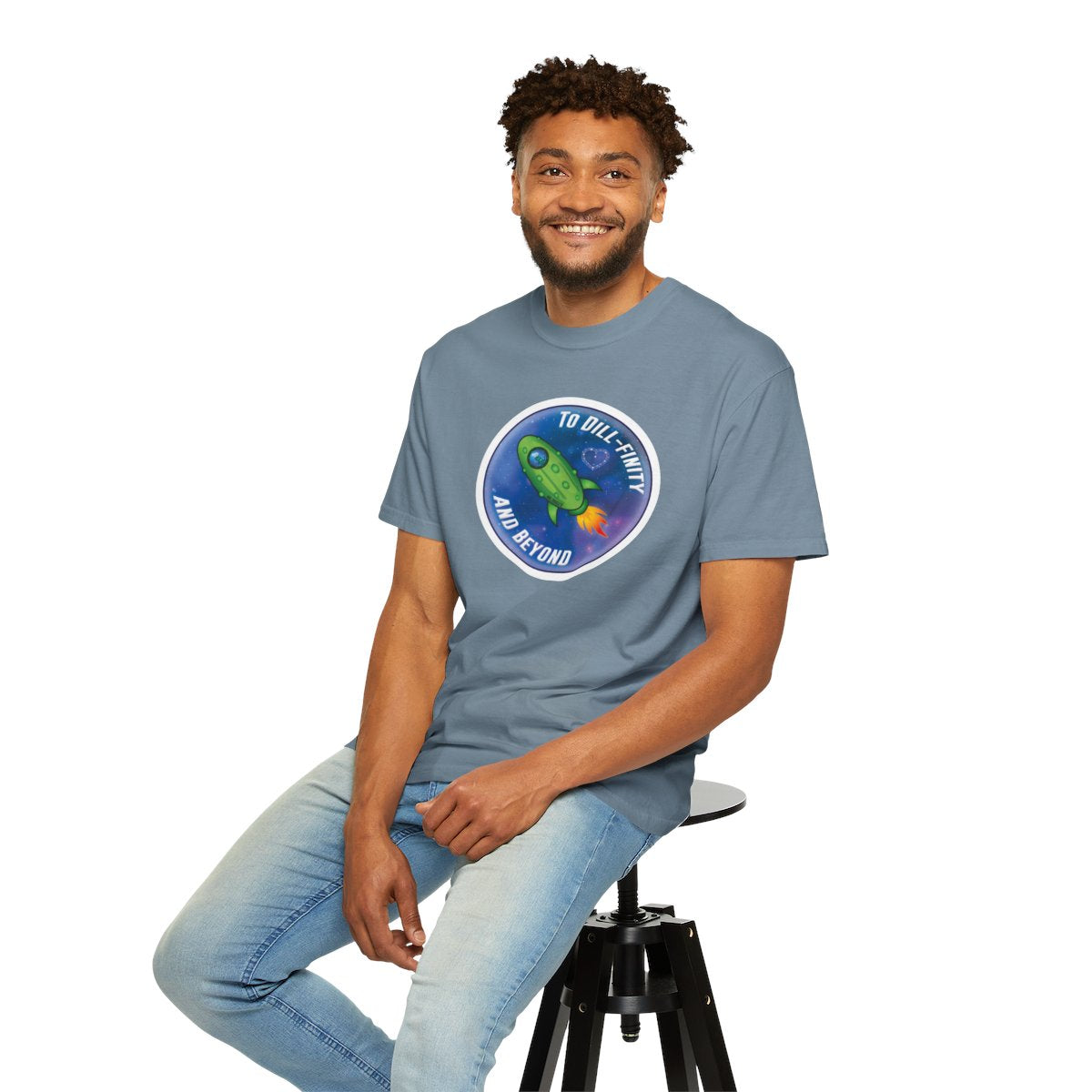 Man wearing a blue t-shirt with a graphic design sitting on a stool against a white background